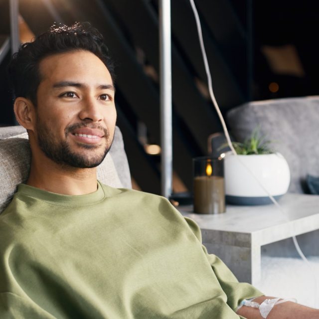 Doctor, man and wellness in clinic with iv drip, natural medicine or discussion for hydration benefits. Healthcare worker, people and talking with intravenous fluid, homeopathic drugs or supplements.