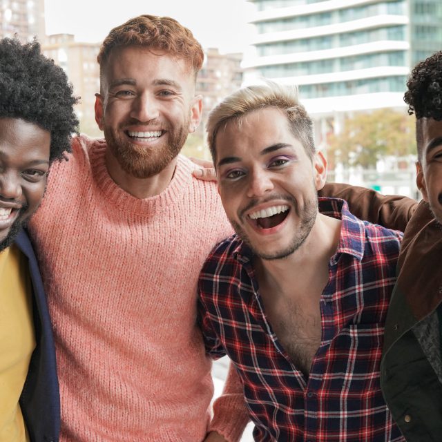 Group of young diverse men smiling on camera in the city - Multiracial male friendship concept