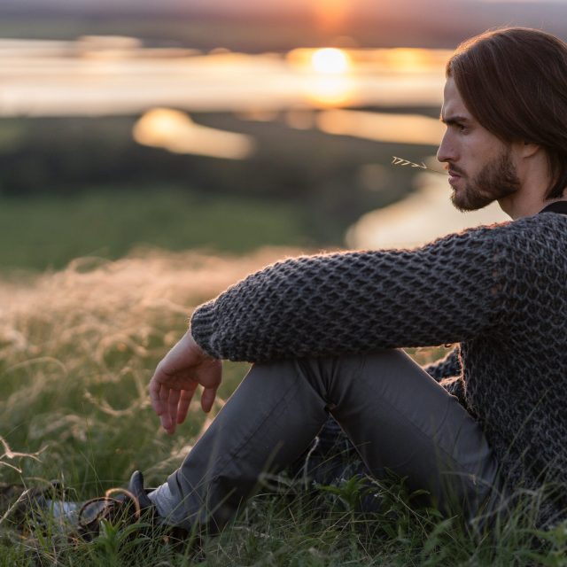 man-relaxing-in-grassy-field-at-sunset-2026-03-16-23-02-03-utc